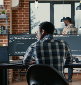 programmer coding laptop sitting down desk with computer